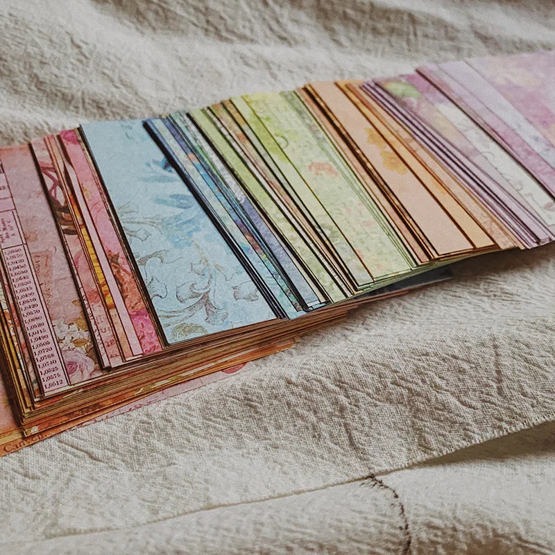 A collection of rainbow textured paper sheets in various shades and patterns laid out on a light fabric.