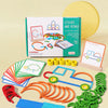 A box of wooden sticks and rings puzzle with various colored pieces laid out on a light background.
