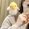 A fluffy yellow cartoon bird plush toy being held by a person's hand.