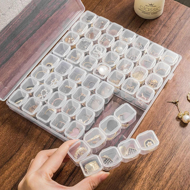 A hand holds an open plastic storage box filled with small clear boxes for craft supplies.