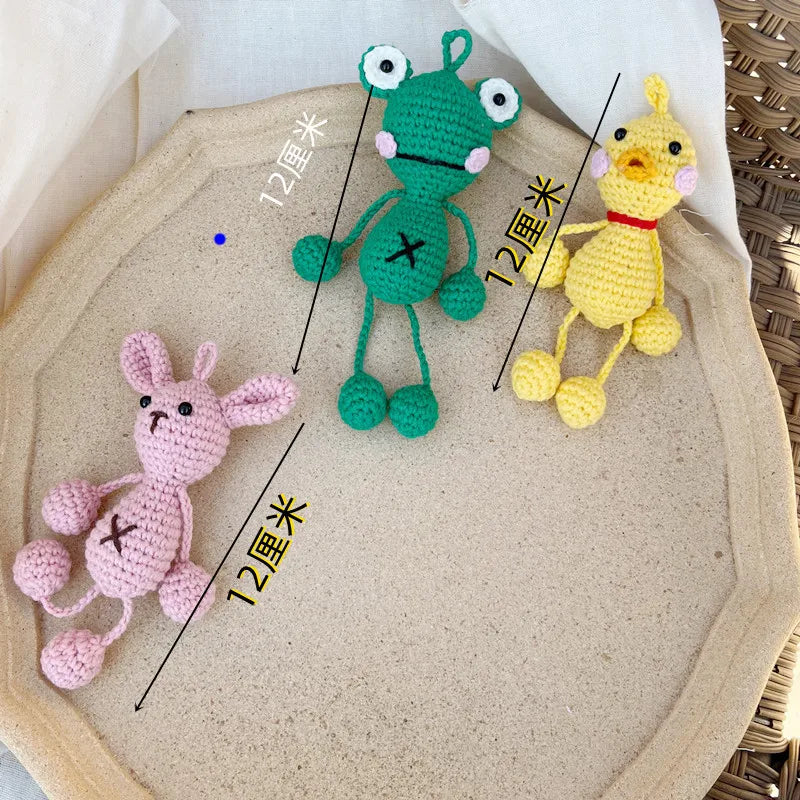 Three handmade crochet frog ornaments in green, yellow, and pink are displayed on a light background.