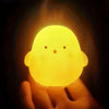 A glowing yellow cartoon duck night light is held in a hand against a dark background.