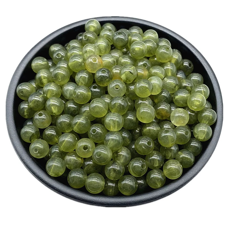 A pile of small, translucent olive green acrylic round beads for jewelry making.