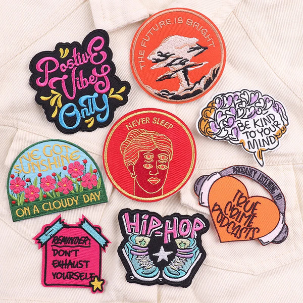 A collection of colorful embroidery iron-on patches featuring phrases like Positive Vibe Only, Never Sleep, and Hip Hop.