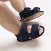 A pair of navy blue breathable first walker sandals for a baby, shown on a child's foot.