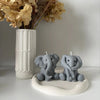 A gray elephant silicone mold resting on a white ceramic dish with dried flowers in the background.