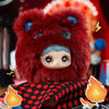 A fluffy red bear plush blind box with blue accents sitting on a black and red patterned cloth.