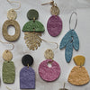 A collection of polymer clay rollers featuring various floral textures and shapes in shades of green, purple, and gold.