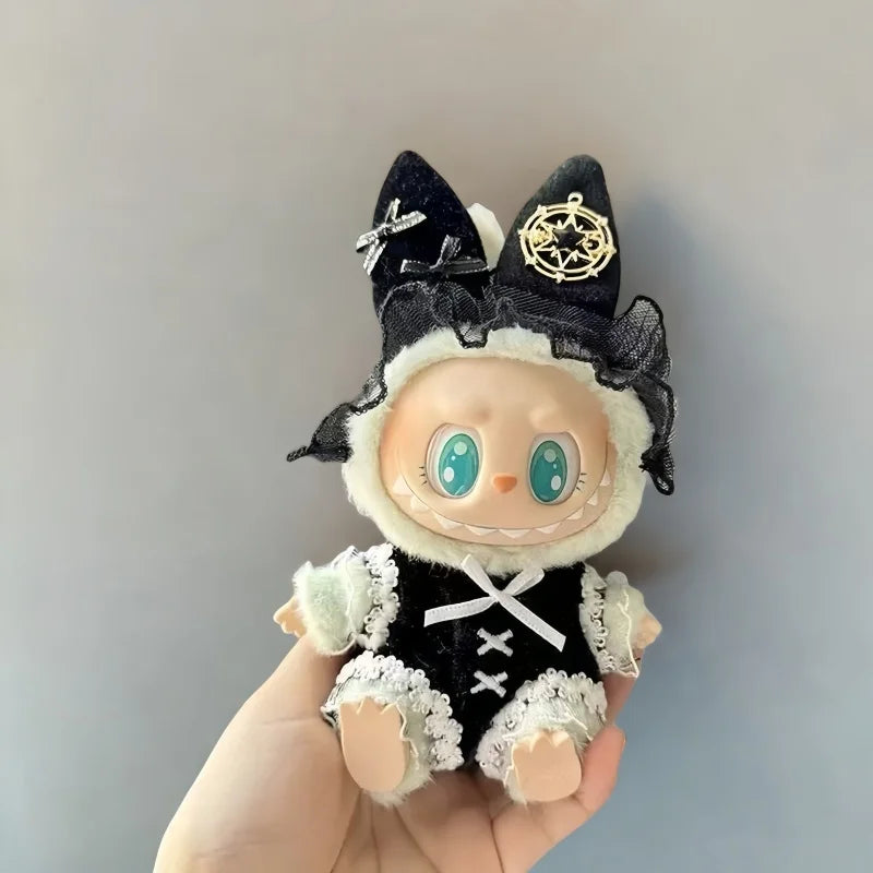 A handmade plush doll dressed in a black and white outfit with gold accents, held in a hand.