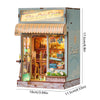 A miniature wooden dollhouse kit featuring a storefront with a striped awning and display items.