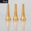 A pair of gold-plated trumpet mouthpieces displayed on a reflective surface.