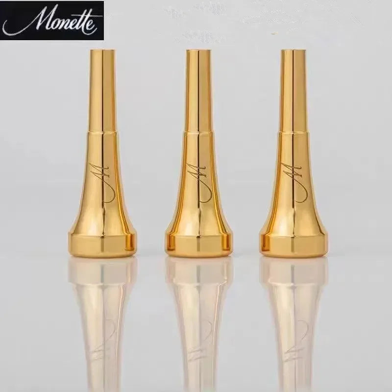 A pair of gold-plated trumpet mouthpieces displayed on a reflective surface.
