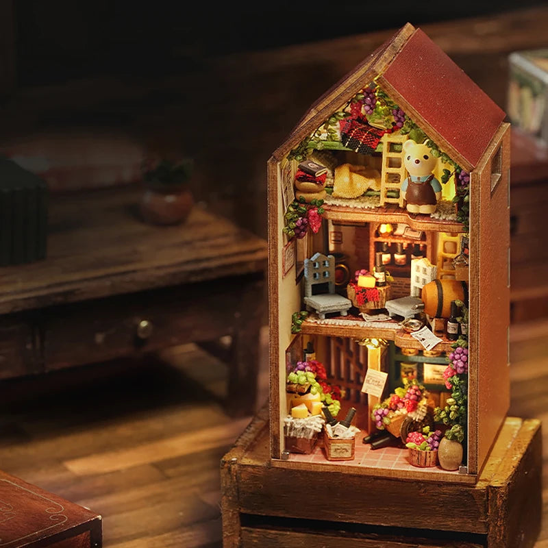 A wooden miniature dollhouse kit featuring a detailed diorama of a cozy, rustic interior with small figures and decorative el
