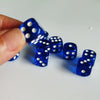 A hand holds a row of blue polka dot dice on a white surface.