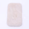 A rectangular, fluffy, light pink faux fur mat used for dollhouse decor.