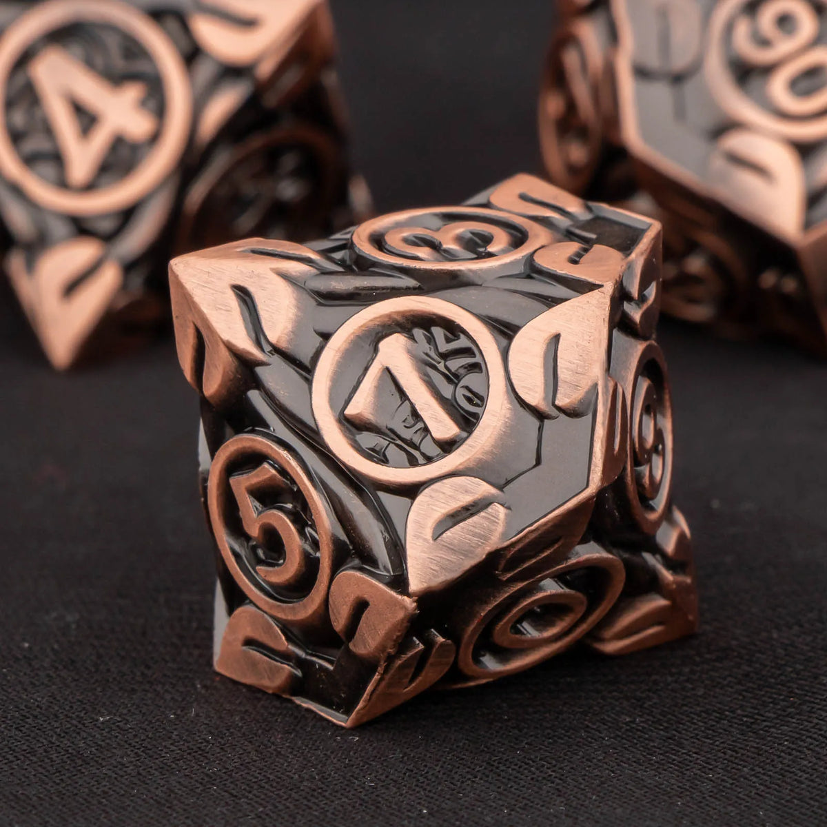 A close-up of a set of metallic dice, featuring numbers and symbols, resting on a dark surface.