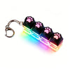 A keyboard keychain fidget toy featuring black silicone paw shapes and a multi-colored LED light.