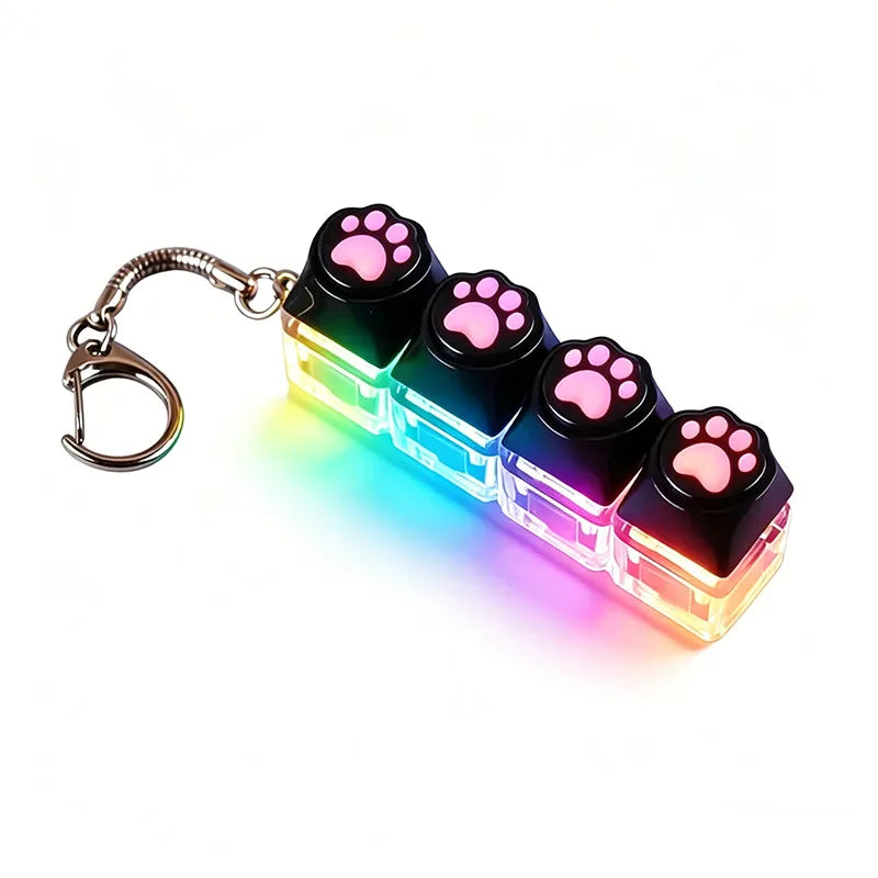A keyboard keychain fidget toy featuring black silicone paw shapes and a multi-colored LED light.