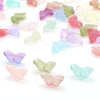 A scattered collection of colorful glass butterfly beads in various shades of pink, purple, green, and blue.