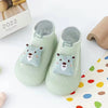 A pair of soft, light green animal-themed socks for babies and toddlers with a fuzzy texture.