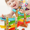 A young girl is playing with a wooden inertia race track toy set featuring various colored vehicles.