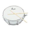 A silver drum with a white head and two maple wood drumsticks resting across the top.