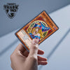 A hand holds a Magic Shark anime dragon PVC card skin sticker featuring a girl with purple hair and a blue outfit.