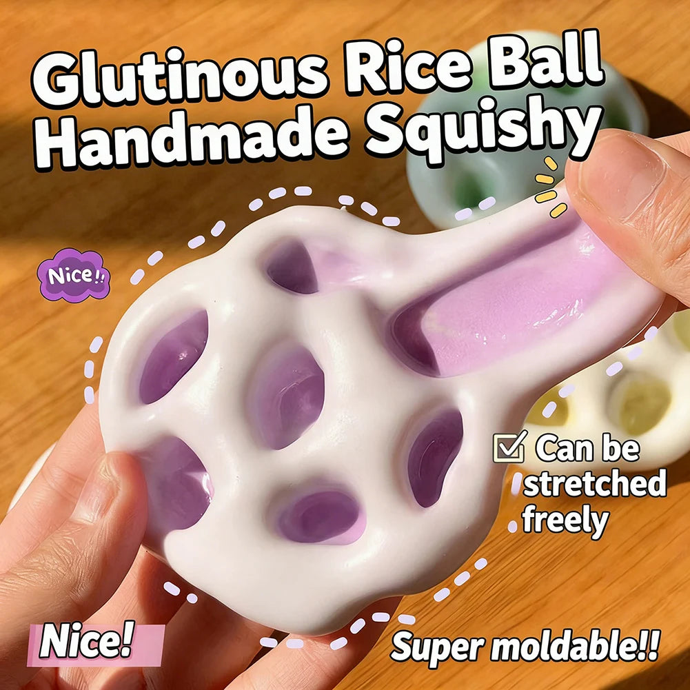 A hand holds a white glutinous rice ball handmade squishy toy with purple accents, demonstrating its moldable texture.