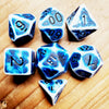 A collection of blue and white polyhedral dice scattered on a wooden surface.