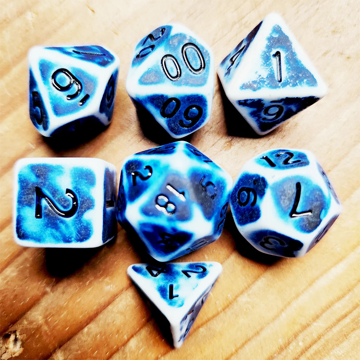 A collection of blue and white polyhedral dice scattered on a wooden surface.