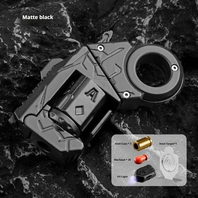A matte black metal gun-shaped fidget slider with various targets and an UV light is shown on a dark surface.