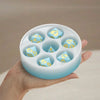 A hand holds a silicone resin mold set with six hexagonal compartments, containing custom dice.
