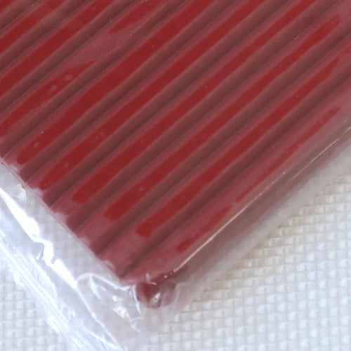 A close-up view of a red polymer clay kit with soft modeling clay packaged in clear plastic.