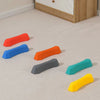 A collection of colorful, non-slip sensory stepping stones in orange, blue, gray, teal, and yellow scattered on a light carpe