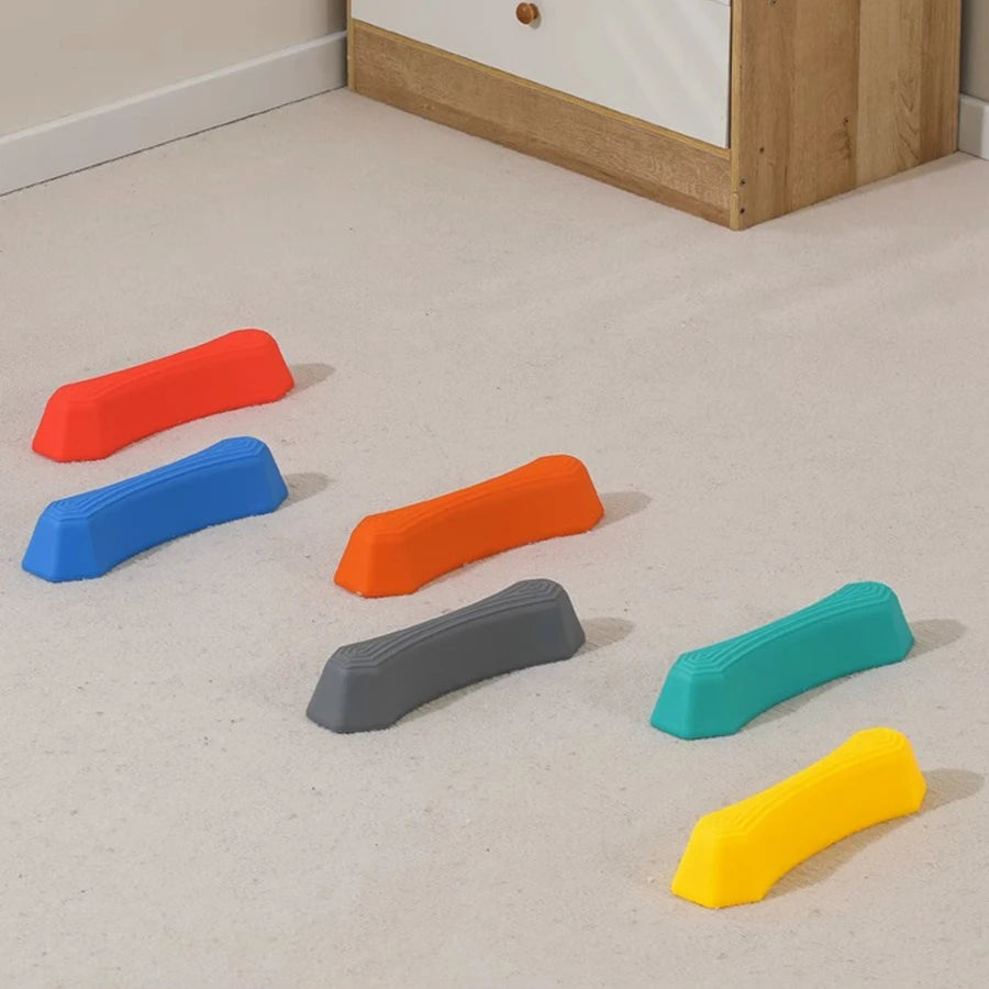 A collection of colorful, non-slip sensory stepping stones in orange, blue, gray, teal, and yellow scattered on a light carpe
