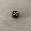 A dark brown acrylic die with white dots is placed on a light wooden surface.