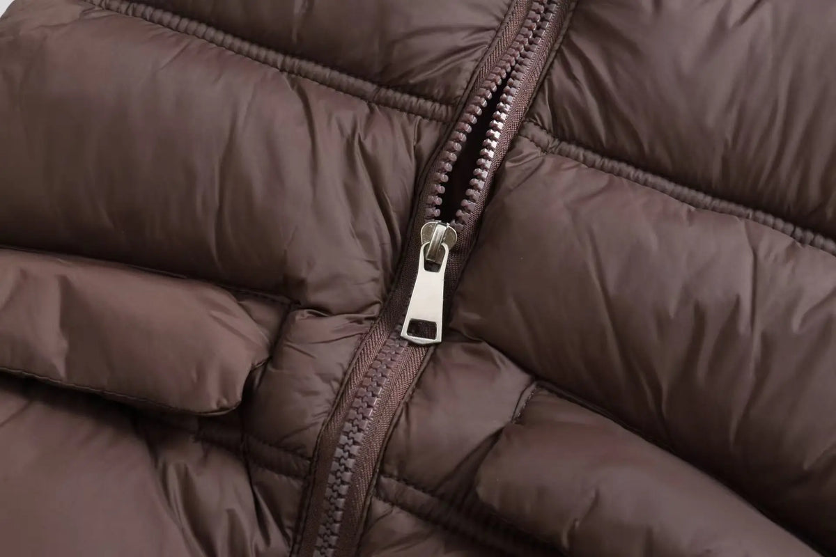 Close-up of a brown padded down vest showing the zipper and quilted texture.