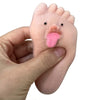 A hand holds a pink silicone fidget toy shaped like a foot with a tongue sticking out.