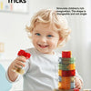 A smiling toddler is building a tower with colorful magnetic blocks on a table.