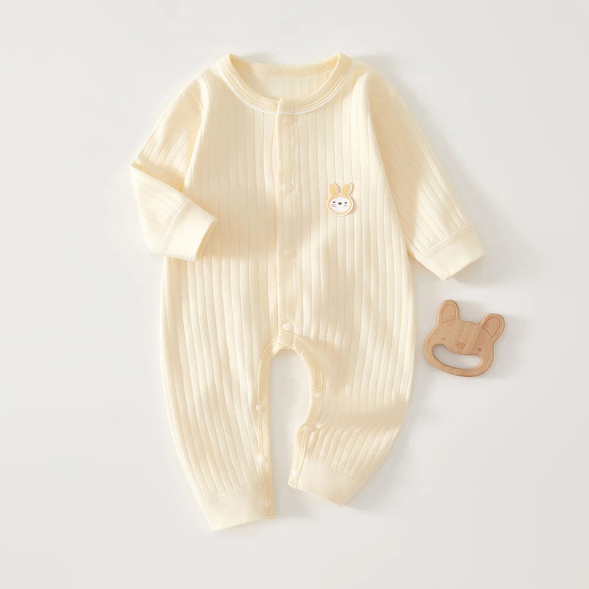 A cream-colored ribbed soft cotton baby romper for newborns and infants with a small bunny embroidery.