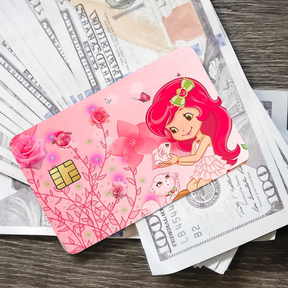 A pink card with a cartoon girl and flowers is placed on top of a stack of paper money.