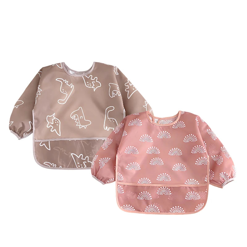 A full-sleeve waterproof baby bib in pink with a white cartoon rainbow design.