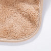 A close-up of a beige, fuzzy cotton baby bib with a snap closure.