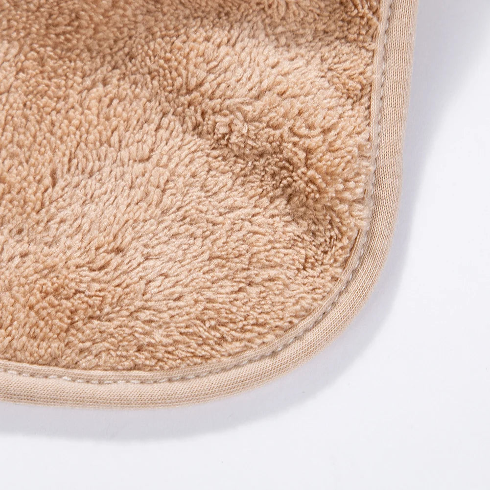 A close-up of a beige, fuzzy cotton baby bib with a snap closure.