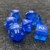 A collection of seven iridescent blue acrylic polyhedral dice scattered on a dark surface.