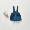 A denim romper for a toddler featuring straps and pockets, displayed on a light gray background.