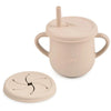 A light beige silicone snack cup with a lid and a small silicone plate is shown.