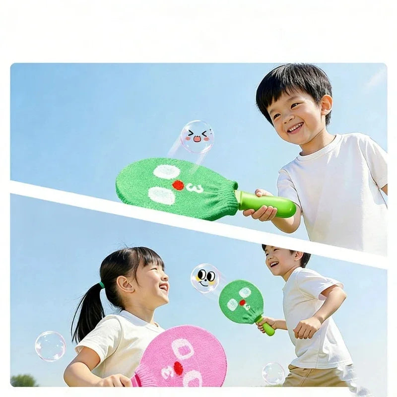 A young boy and girl are playing with a handheld smoke bubble wand outdoors under a blue sky.