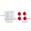 Moule en silicone blanc avec quatre creux circulaires et trois pièces sphériques rouges.
