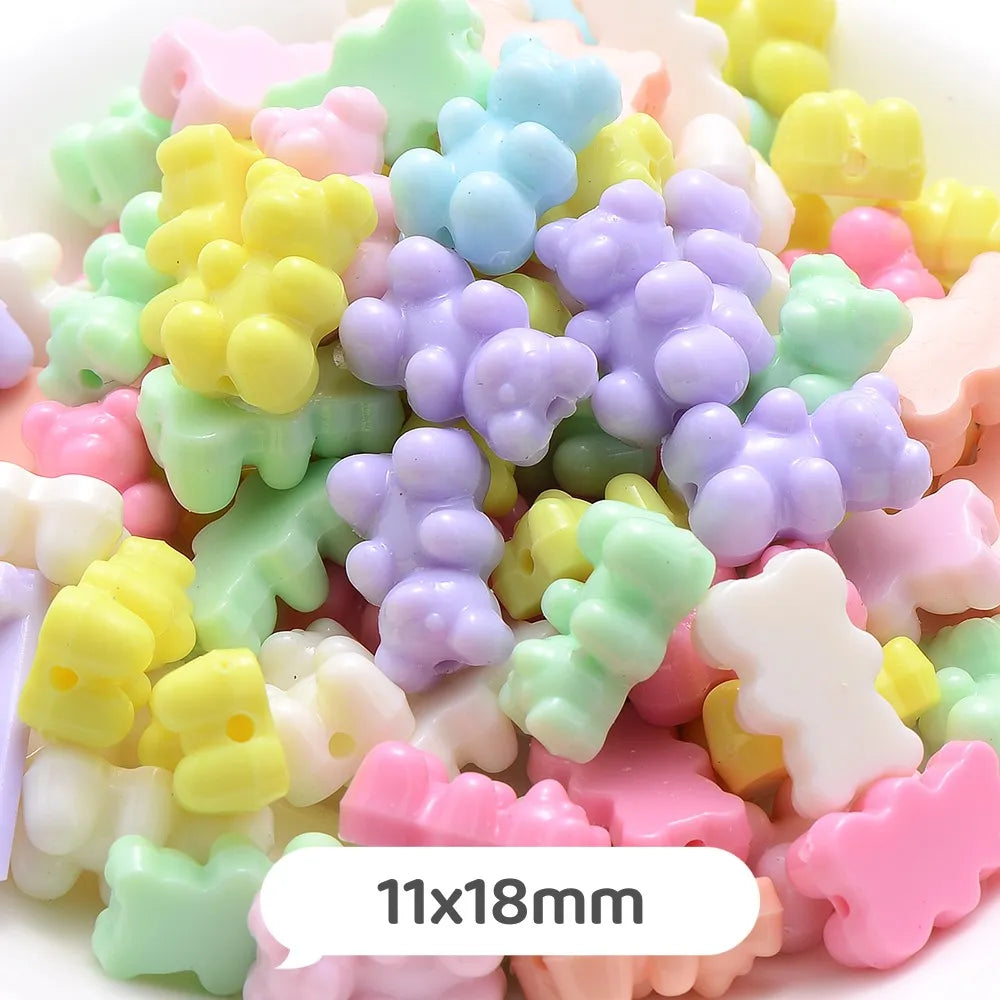 A close-up of various pastel bear-shaped acrylic craft beads in shades of yellow, green, purple, and pink.